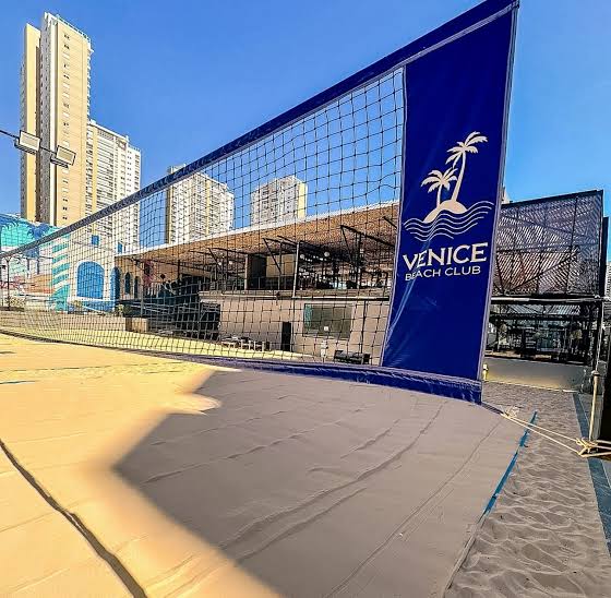 Quadra de areia do Venice Beach Clube com o skyline de São Paulo ao fundo